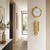 Gold-colored wall clock with decorative pendulum on the hallway wall