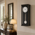Wall clock with black frame, white dial, and glass pendulum weight