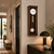 Walnut wood wall clock with pendulum, glass front, and round white dial