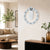 Wall clock with light-colored casing, light blue ring, black numbers 1 to 12, and silver hands