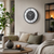 Wall clock on the wall with a black case, gray dial, green numbers, and marble