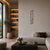 Wall clock on the wall above sofa, moss and wood slices in dark frame