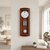 Wooden wall clock in wooden frame with round dial, pendulum, and large gong, on the wall