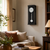 Wall clock on the wall with a black case, white dial, and round pendulum weight