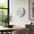 Round LED word clock with gray dial, mounted on a white wall