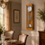 Wooden wall clock with round dial, glass window, and metal pendulum