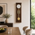 Walnut-colored wall clock with round dial and brass pendulum, round yellow weight