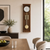 Wooden wall clock on the wall made of brown wood with a white dial, gold-colored gong rods