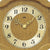 Nahaufnahme: Wanduhr-Ziffernblatt aus Eiche mit goldenen Zeigern und AMS-Logo
