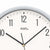 Close-up of a wall clock face with numbers 11-12 and hands, silver outer ring