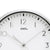 Close-up of a radio-controlled clock: white dial with AMS logo and hands