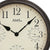 Detail der Wanduhr: brauner Metallrand, beiges Zifferblatt mit Temperatur-Skala im Kreis