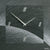 Nahaufnahme Wanduhr aus Naturschiefer mit Airbrush-Linien, römischen Ziffern und Zeigern