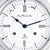 Close-up of dial: Roman numerals, blue hands, "Ship's Bell" bell symbol
