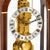 Detail of the wooden table clock: gold-colored mechanical movement with Roman numerals