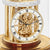 Close-up of table clock: gold skeleton dial with Roman numerals and hands