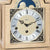 Wooden mantel clock face with moon phase window, Roman hour markers, and black hands
