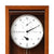 Wall clock face in wooden frame with large numbers, hands, and central drive.