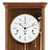 Close-up of wooden wall clock: white dial with Roman numerals and gold border